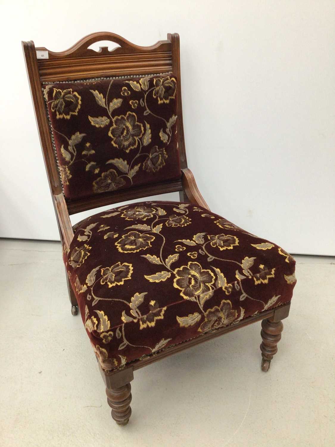 Edwardian walnut framed easy chair with upholstered seat and back on turned front legs and castors