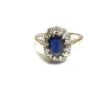 Sapphire and diamond cluster ring with an oval mixed cut blue sapphire surrounded by a border of sin