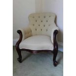 Victorian mahogany framed arm chair with buttoned cream upholstery, on scroll carved legs terminatin