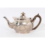 Edwardian silver teapot of cauldron form with embossed floral and scroll decoration,