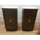 Pair of Edwardian inlaid mahogany bedside cupboards, the bow fronted white marble tops above slightl