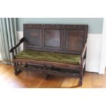 Late 17th/early 18th century oak settle, the top rail carved with scrolling foliate decoration over