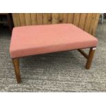 Rectangular pink upholstered stool on shaped legs joined by stretchers