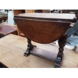 Oak drop leaf table on turned end standards and a nest of three oak occasional tables