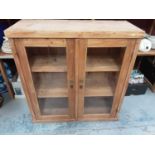 Pine bookcase with shelved interior enclosed by two glazed doors, 97cm wide, 38.5cm deep, 100.5cm hi