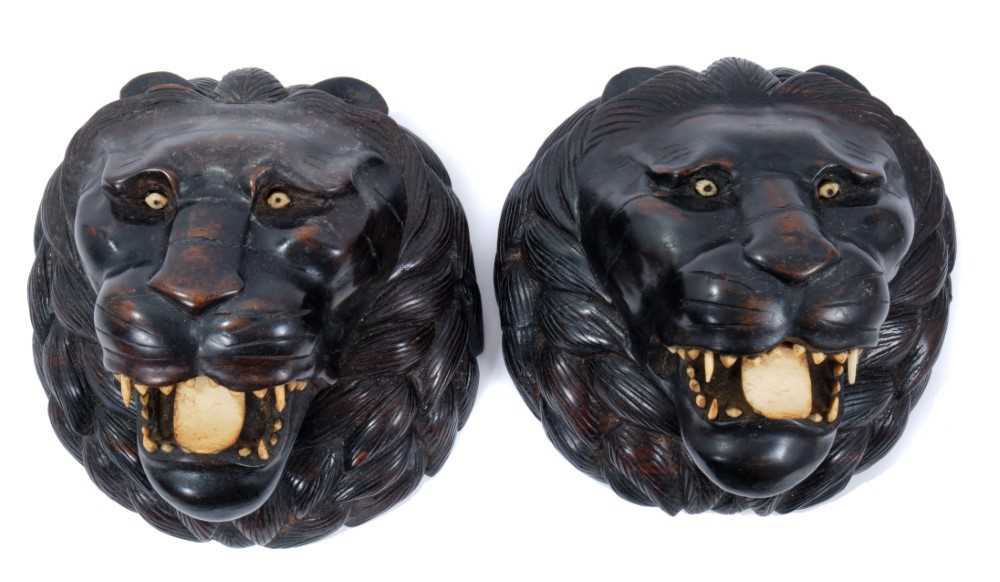Pair of Indian carved wooden lion's heads with bone eyes, teeth and tongue
