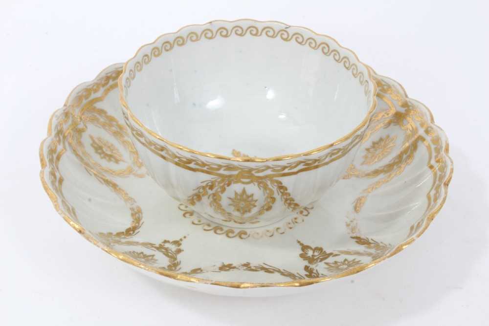 Worcester fluted tea bowl and saucer, circa 1775-80, decorated in gilt with swags and other patterns