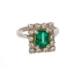 Emerald and diamond cluster ring with a rectangular step cut emerald surrounded by a border of fourt
