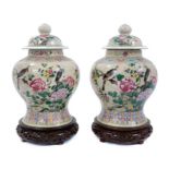 Pair of Chinese famille rose porcelain crackle-glazed jars and covers with carved hardwood stands, a