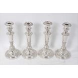 A set of four Old Sheffield plate candlesticks with scroll, shell and floral borders