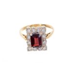 Garnet and diamond cluster ring with a rectangular step cut garnet surrounded by a border of single