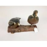 Two painted wooden decoy pigeons mounted on a log