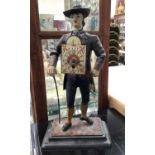 Cast metal painted figure of a gentlemen with a clock strapped to his chest and back