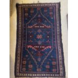 An antique Eastern rug with geometric medallions on blue and red ground, 130cm x 82cm, together with