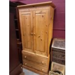 Victorian style pine wardrobe with two panelled doors enclosing hanging rail, and two drawers below,