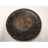 French treen bread board, carved in relief with a motto and foliate patterns, 28cm diameter