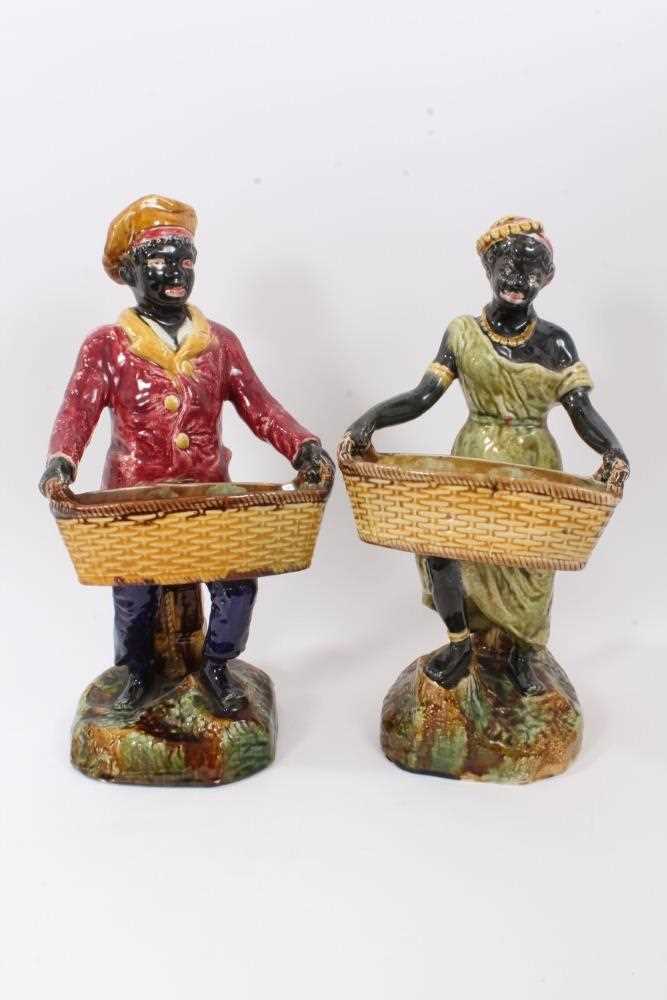 Pair of continental majolica figures, late 19th century, shown holding baskets and standing on grass