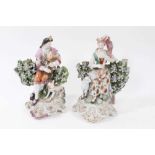 Pair of Derby figures of musicians, with a dog and sheep by their sides, seated within floral encrus