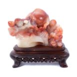 Chinese carved hardstone group of deity figures and a peach, raised on wooden stand