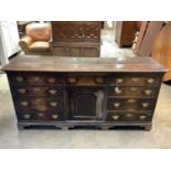 18th century and later oak dresser base,with central fielded panel cupboard and nine drawers, raised