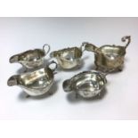 Group of five silver sauce boats of conventional form with scroll handles (Various dates and makers)