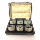 Set of six silver napkin rings with engine turned decoration and engraved initials, and family crest