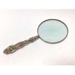 Circular magnifying glass with ornate Victorian silver handle.