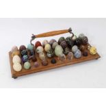 Collection of miniature carved stone and other specimen eggs, housed on wooden stand, approximately