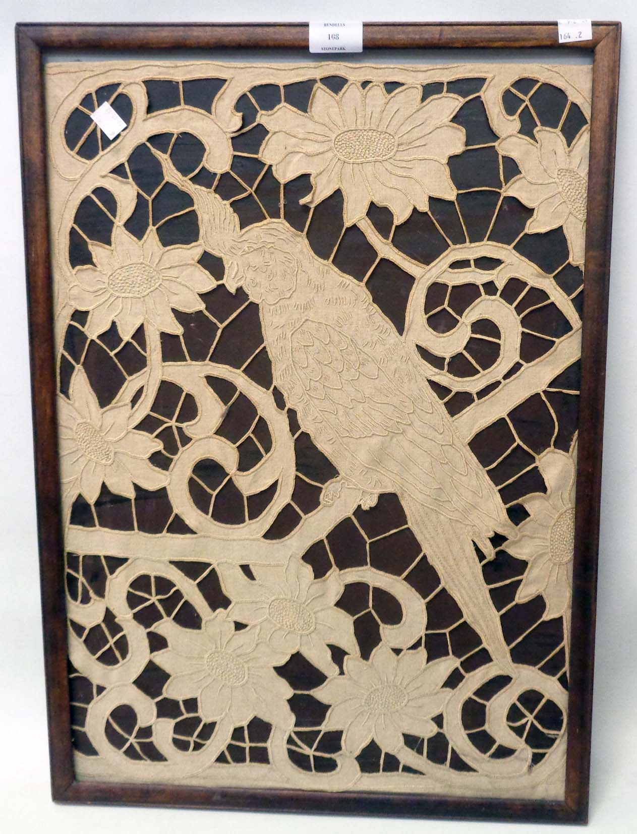 A framed embroidered lace style picture panel, depicting a perching cockatoo