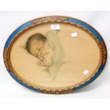 A decorative oval framed coloured print, depicting a sleeping baby