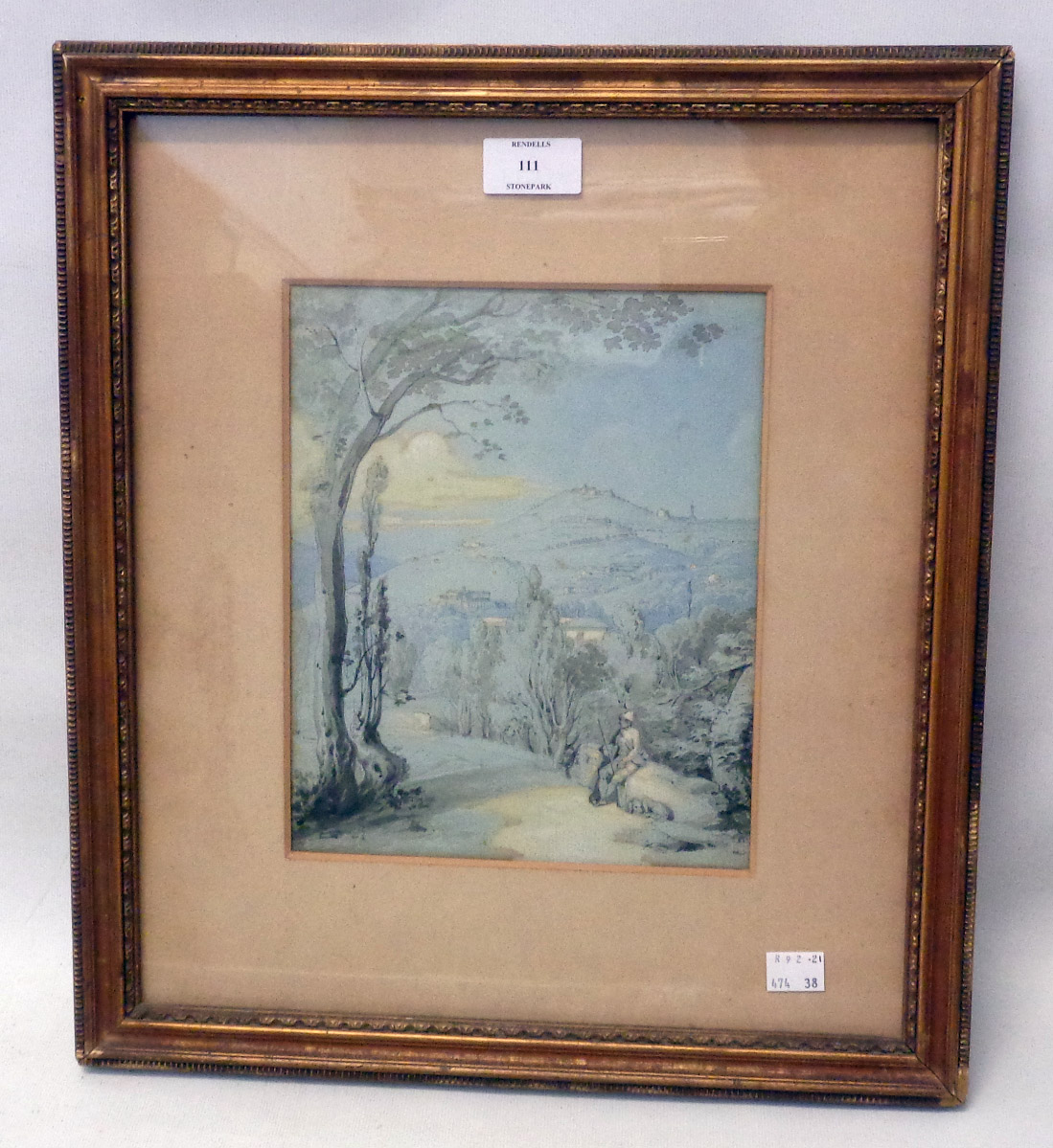 A gilt framed watercolour, depicting a figure sitting on a track with buildings on hill in