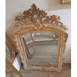 An antique gilt wood and gesso framed wall mirror with slightly domed oblong plate - the ornate