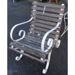 A heavy wrought iron framed elbow garden chair with wooden slats