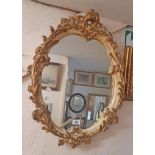 A 50cm wide vintage parcel gilt and painted plaster framed ornate oval wall mirror