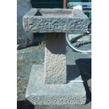 A concrete garden square form bird bath