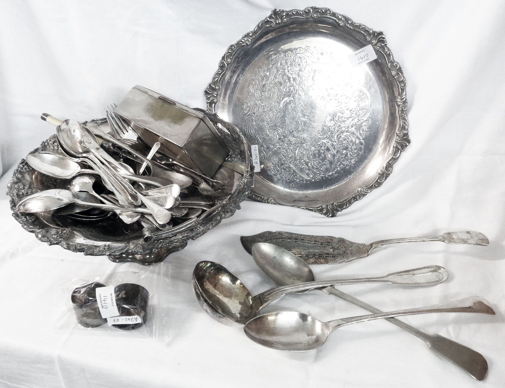 A silver plated cake basket containing a quantity of assorted cutlery, including two basting