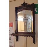 An Edwardian stained walnut framed mirror backed wall shelf with bevelled plate and pierced