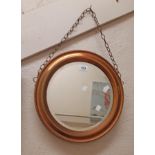 A 39cm diameter 20th Century coppered metal framed bevelled wall mirror by Nestor, on chain
