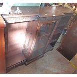 A 1.38m early 20th Century polished oak break front bookcase with blind fretwork decoration, central