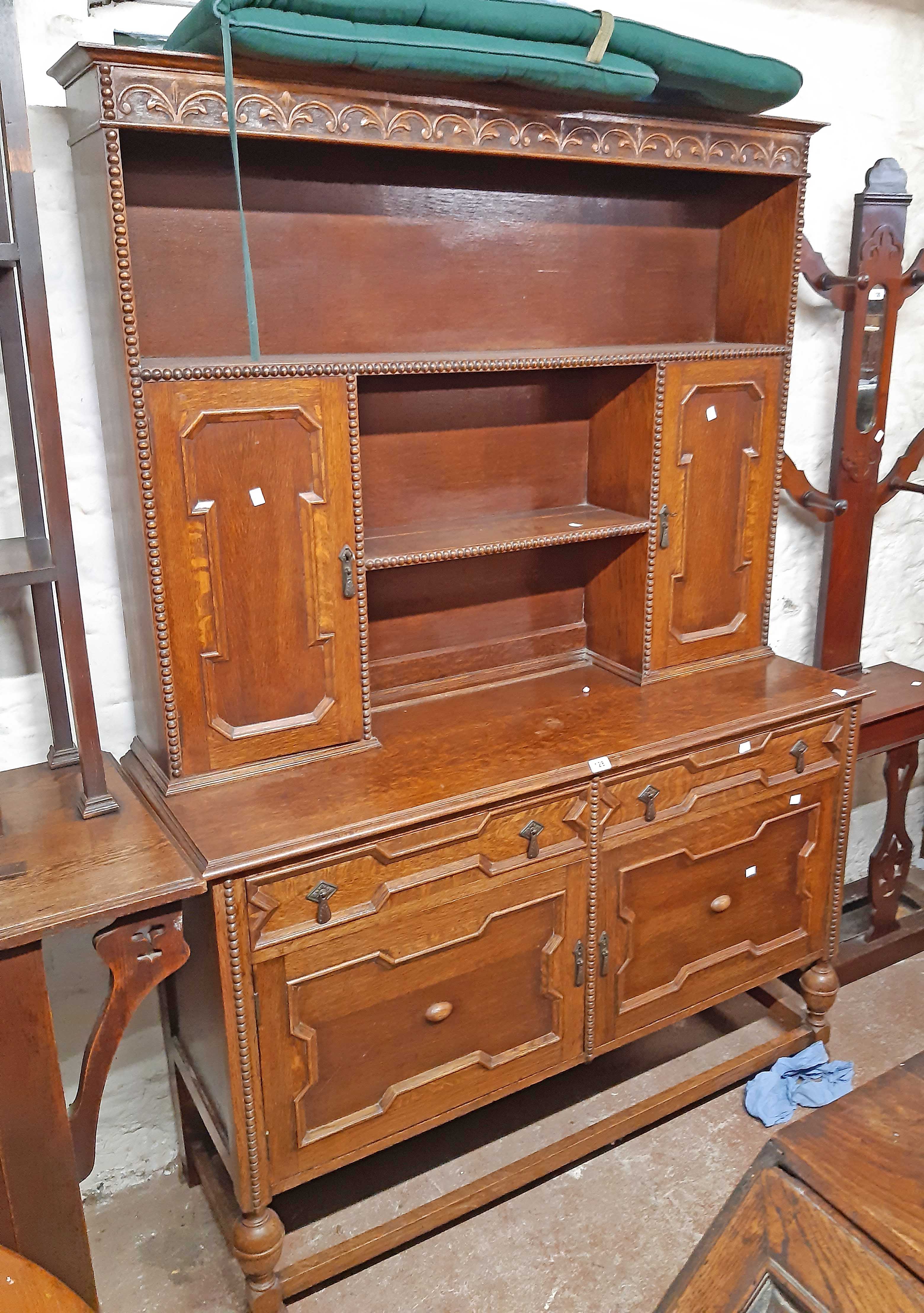 A 1.37m early 20th Century polished oak two part dresser with central shelves, flanking panelled