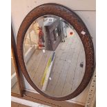 A 69cm wide 1920s oak framed bevelled oval wall mirror with blind fretwork style border