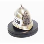 A small plated metal Metropolitan Police helmet deskweight with circular base
