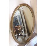 An old gilt gesso framed bevelled oval wall mirror - a/f