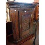 A 69cm antique oak wall hanging corner cabinet with dentil cornice and carved panel door