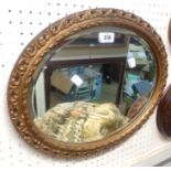 A gilt framed bevelled oval wall mirror with decorative pierced border