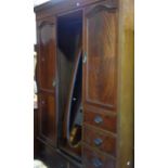 A 1.8m Edwardian flame mahogany veneered and strung triple wardrobe with central bevelled oval