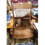 An early 20th Century oak framed high stick back elbow chair with swept armrests and moulded