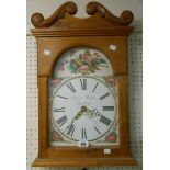 A modern pine wall timepiece in the style of a longcase clock hood with decorative dial and