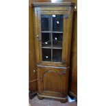 A 65cm reproduction antiqued oak corner cabinet with glazed panel door to top, canted sides and