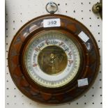 A 22cm diameter early 20th Century carved walnut framed aneroid wall barometer with petal border and